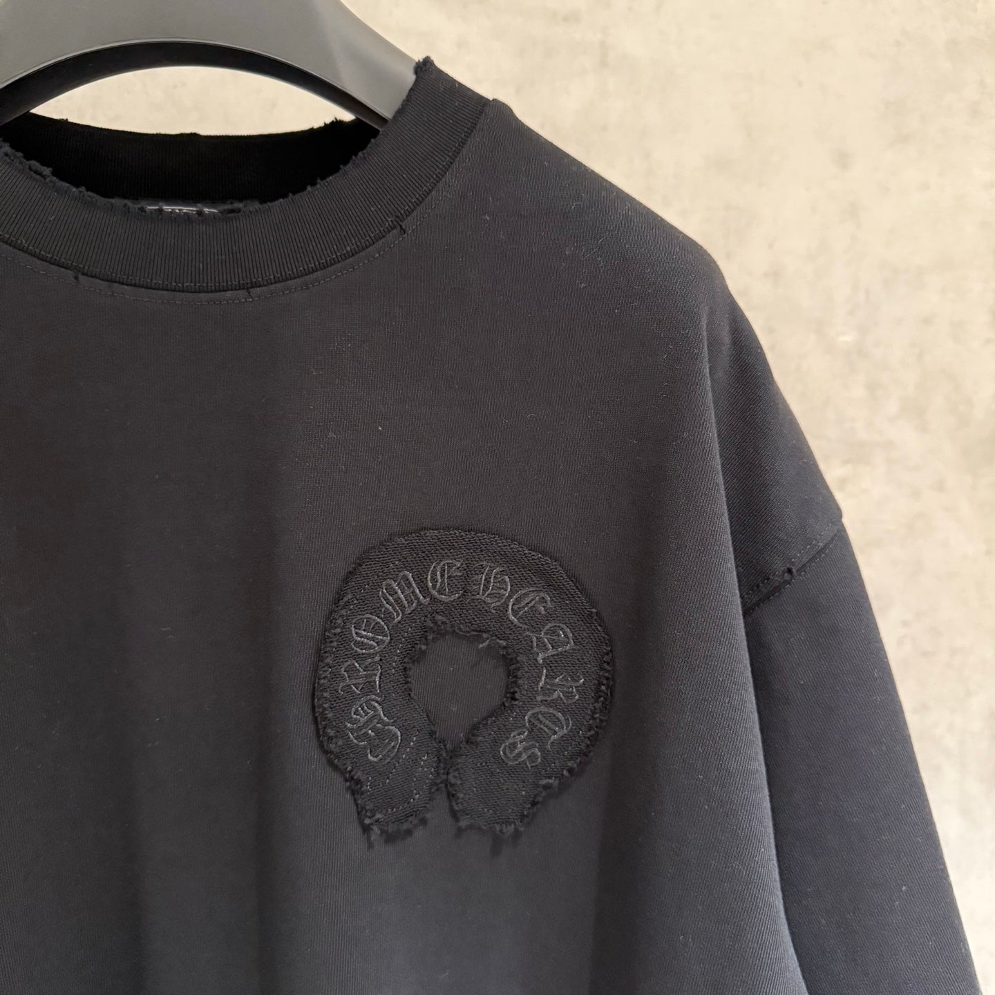 Black T-shirt with round chest emblem and short sleeves detail