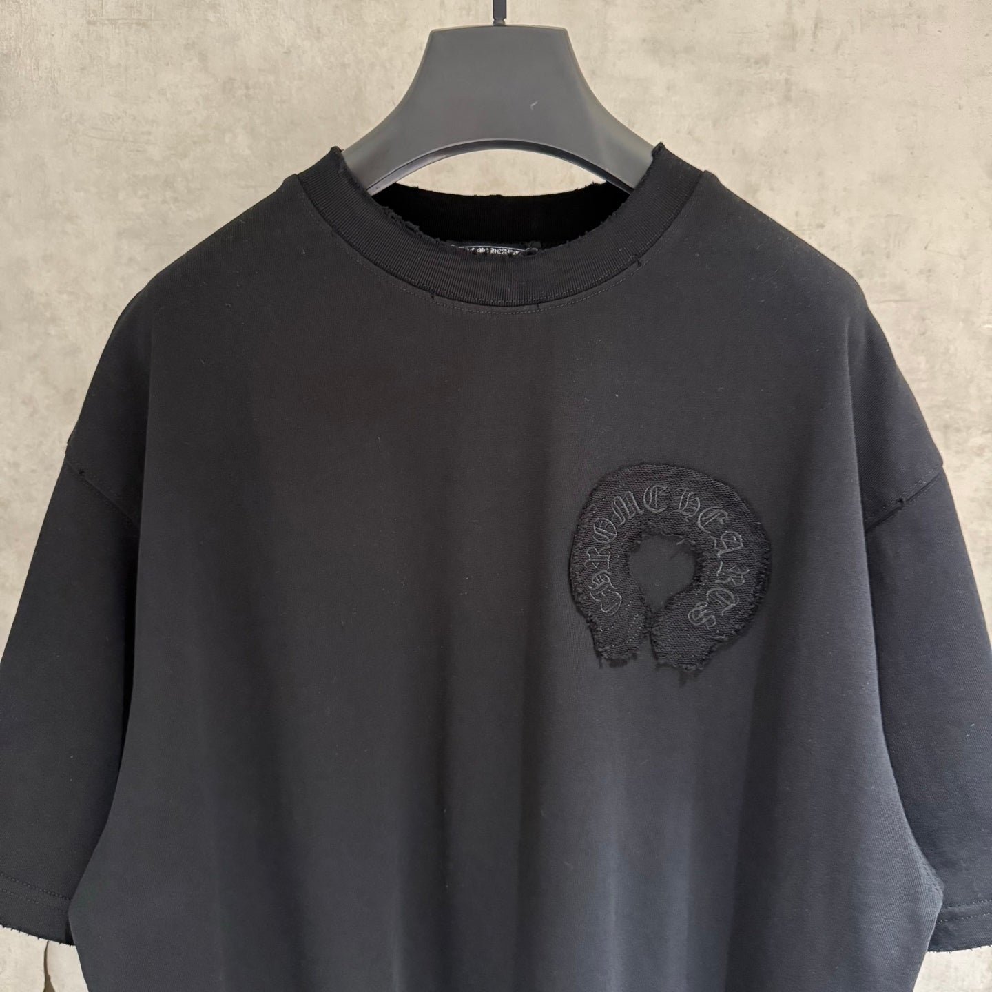 Black short-sleeve T-shirt with crew neckline and round chest emblem close-up