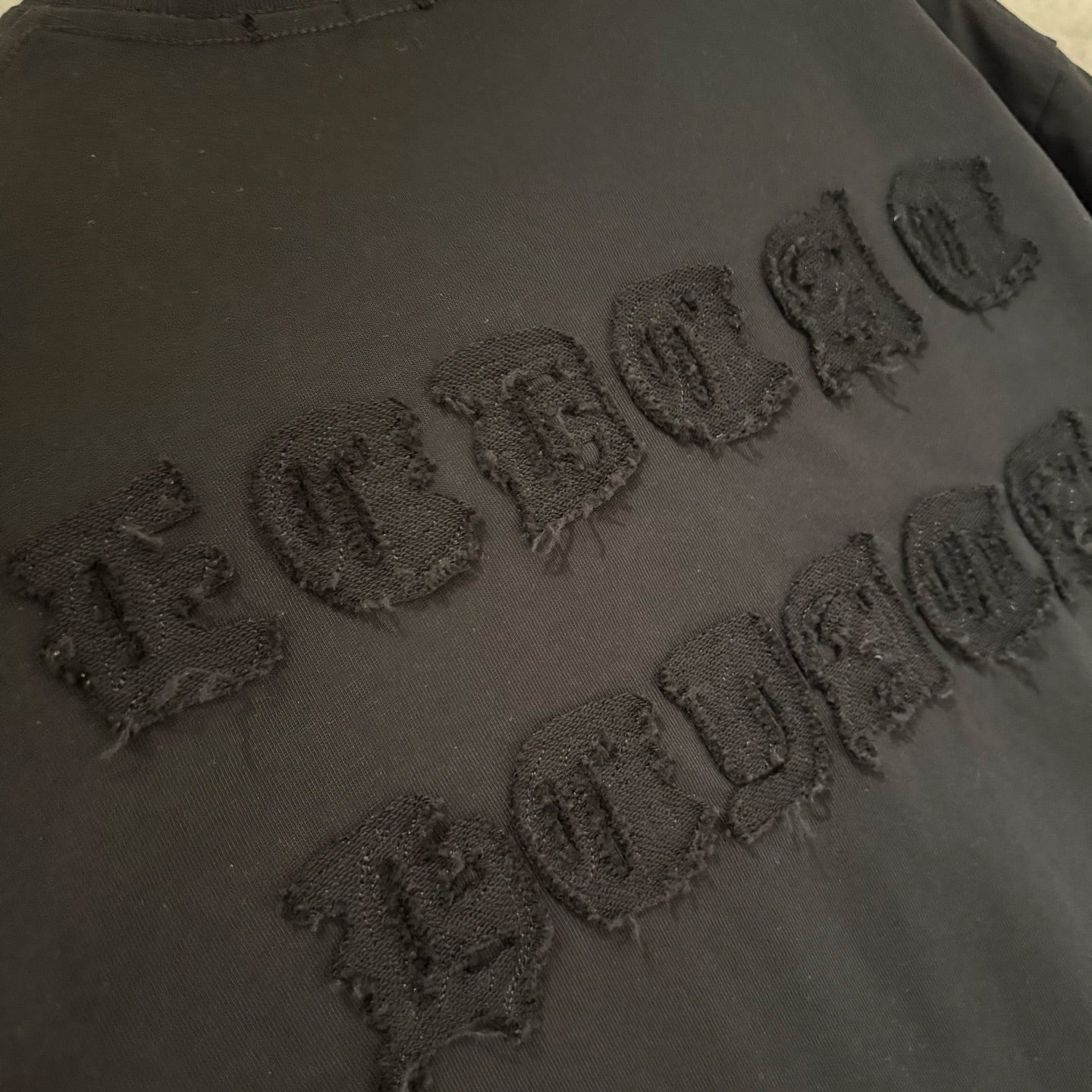 Black T-shirt with raised embossed wordmark text detail