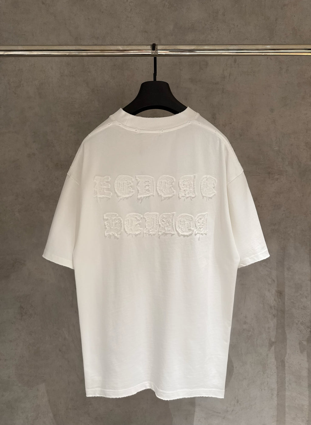 White crew-neck short-sleeve T-shirt with large raised embroidered logo on back.