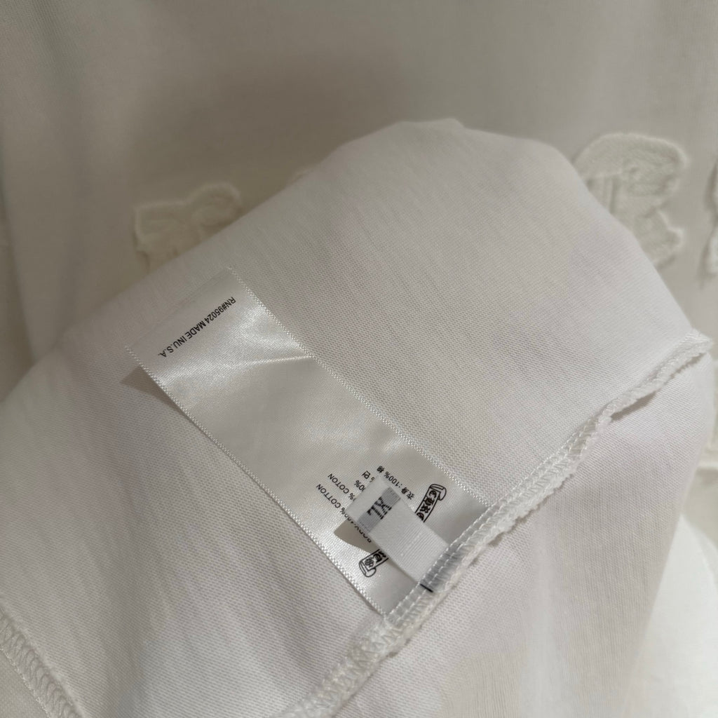 White T-shirt interior hem with printed care label and stitched side edge.