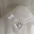 White T-shirt interior hem with printed care label and stitched side edge.
