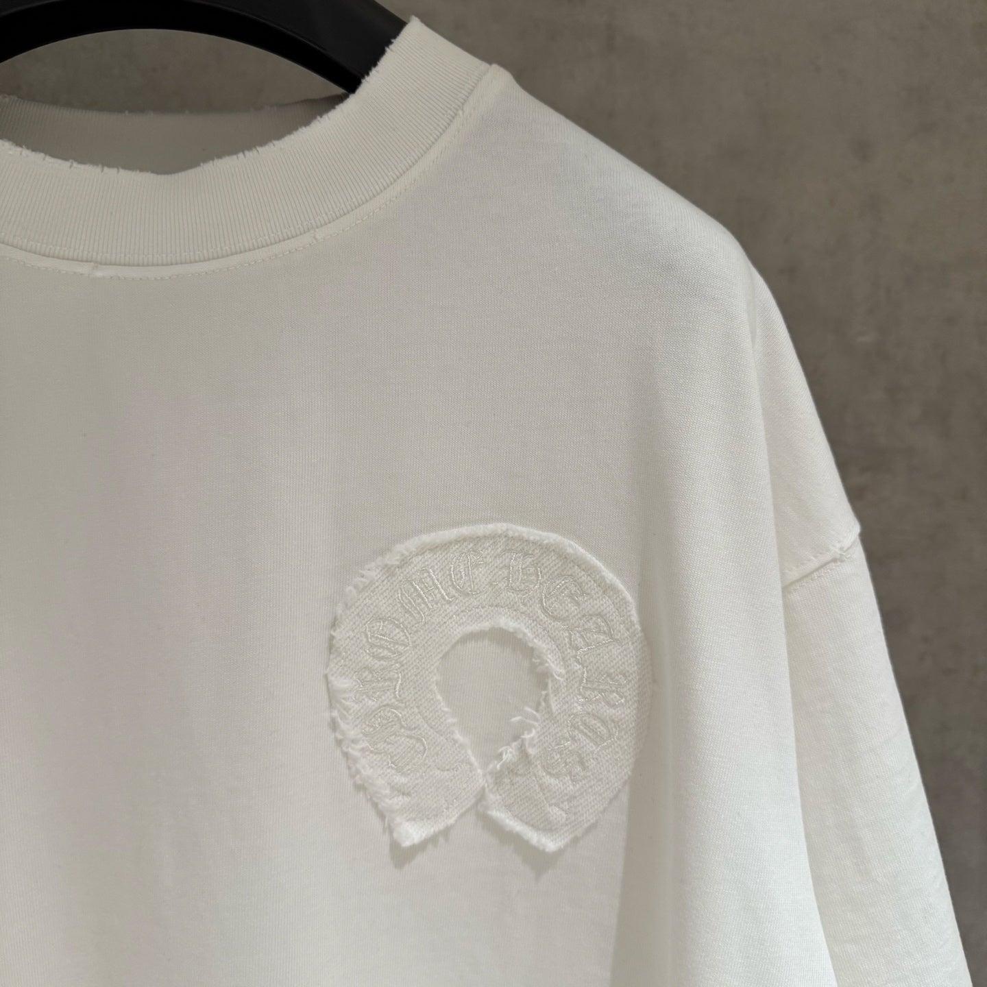 White crew-neck short-sleeve T-shirt with raised embroidered logo on chest.