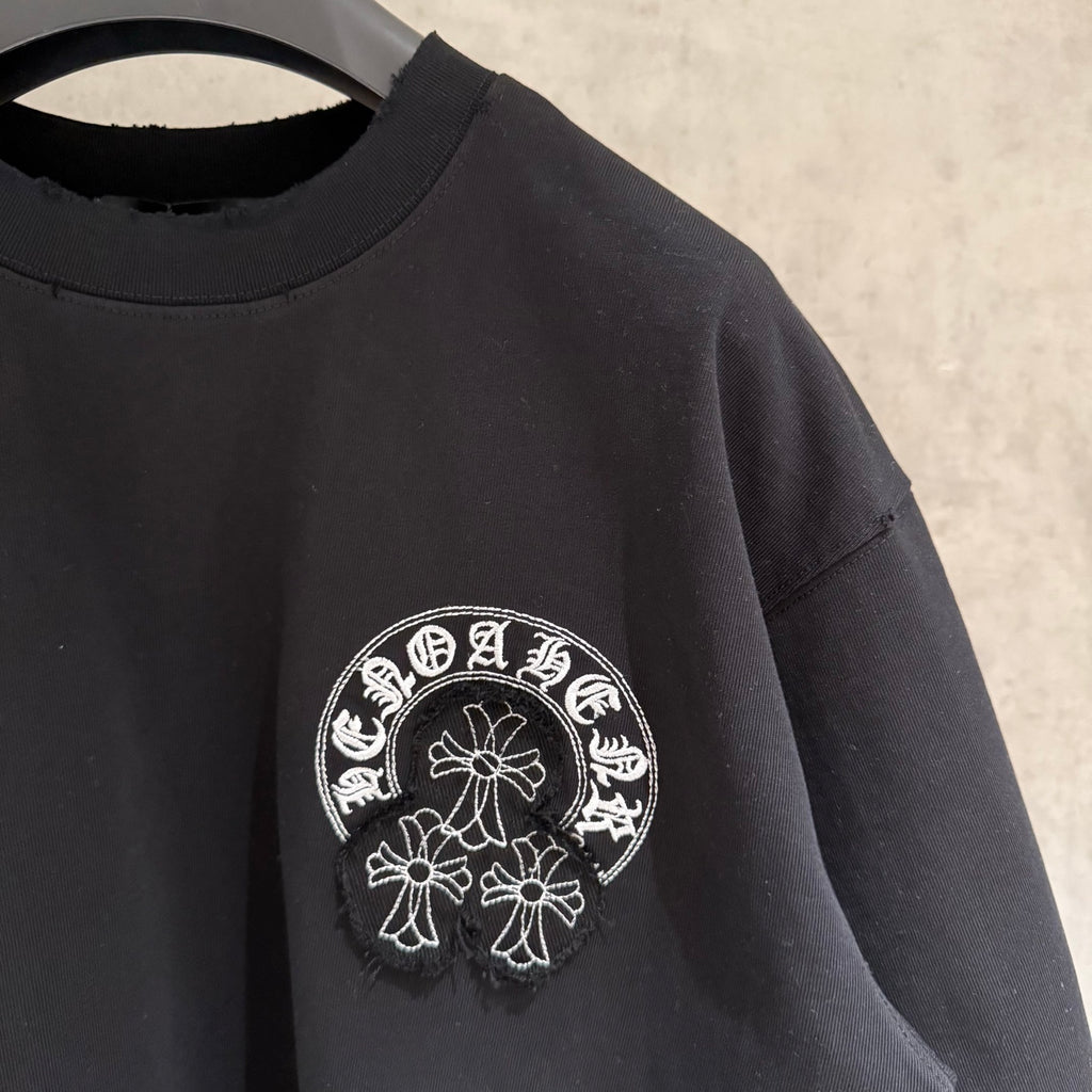 Black short-sleeve T-shirt with small white circular side chest graphic