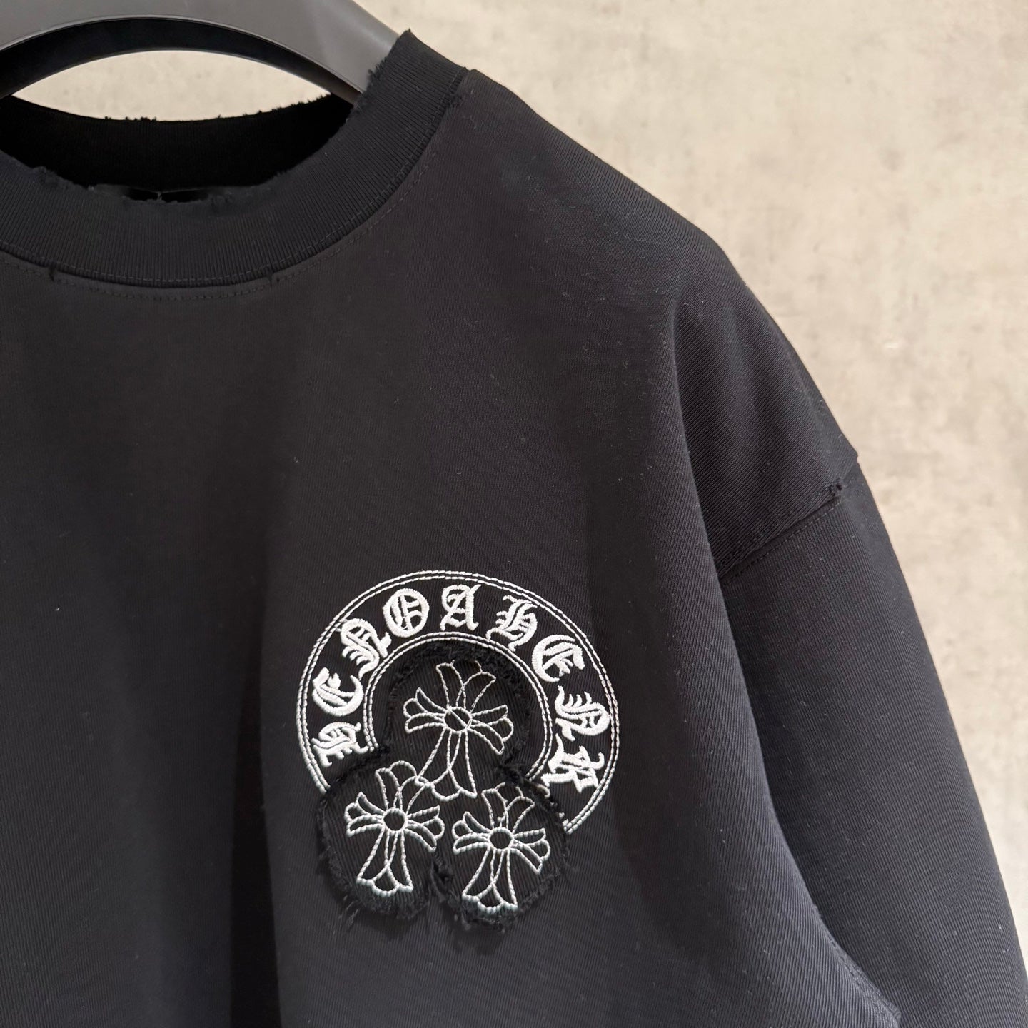 Black short-sleeve T-shirt with small white circular side chest graphic