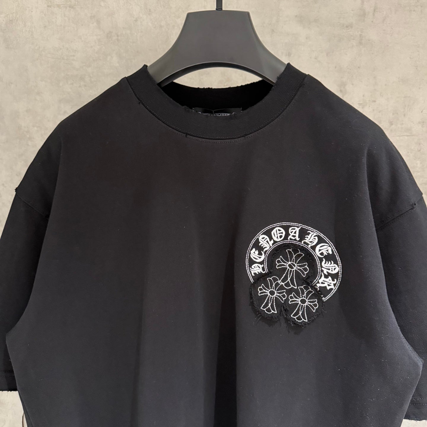 Black short-sleeve T-shirt with crew neck and small white circular chest graphic