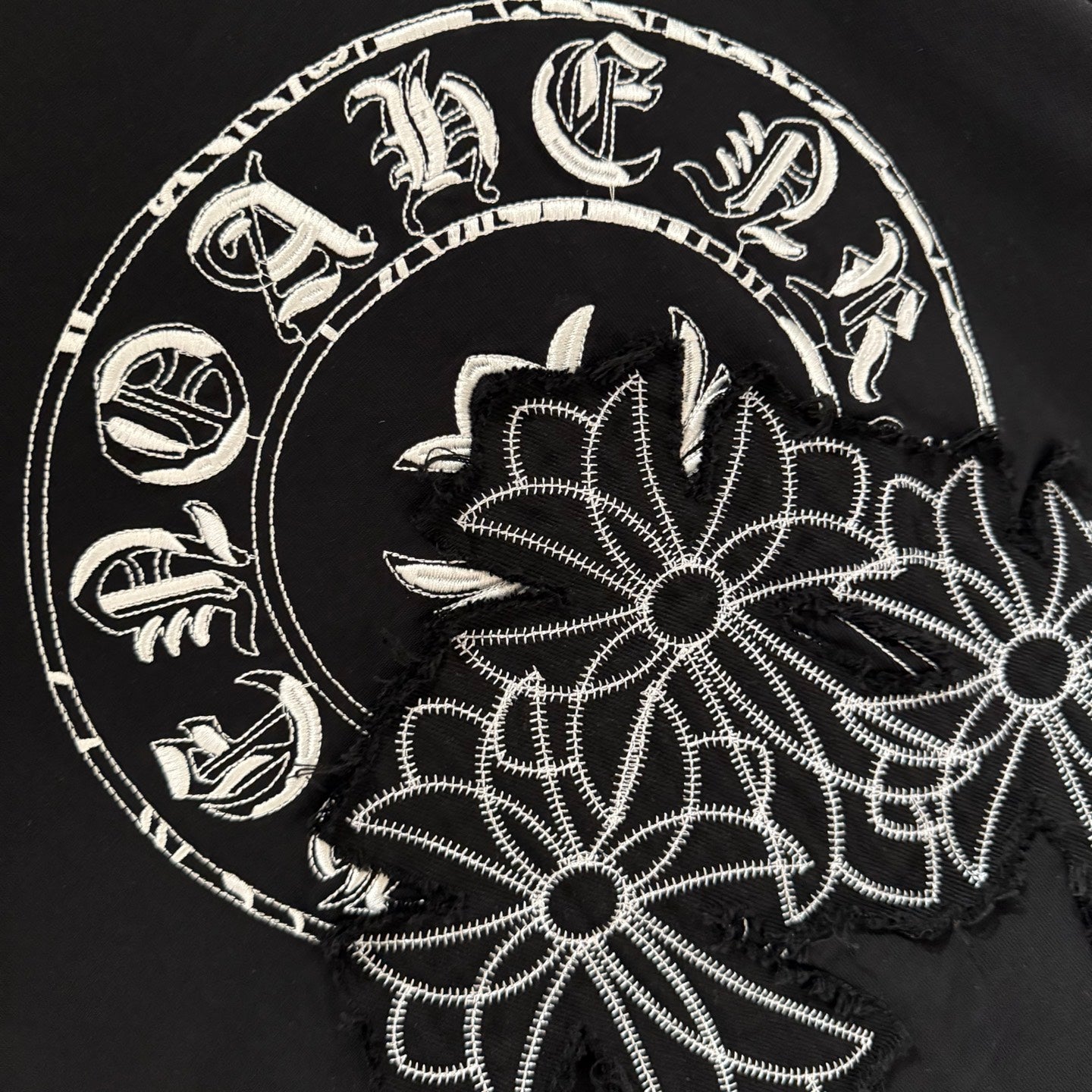 Close-up of white floral circular graphic on black short-sleeve T-shirt