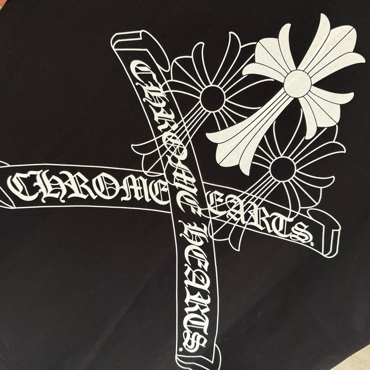 Black short-sleeve T-shirt close-up of white stylized cross graphic