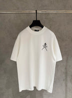 White short-sleeve T-shirt with small black sword-and-flower chest graphic