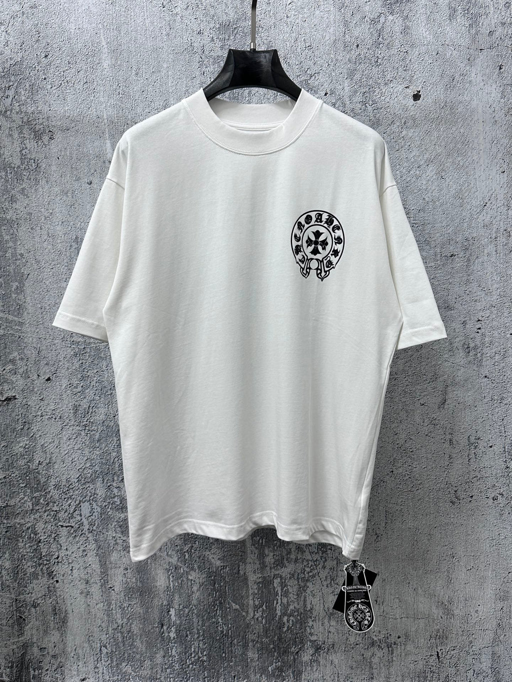 White short-sleeve T-shirt with small black circular graphic on the chest