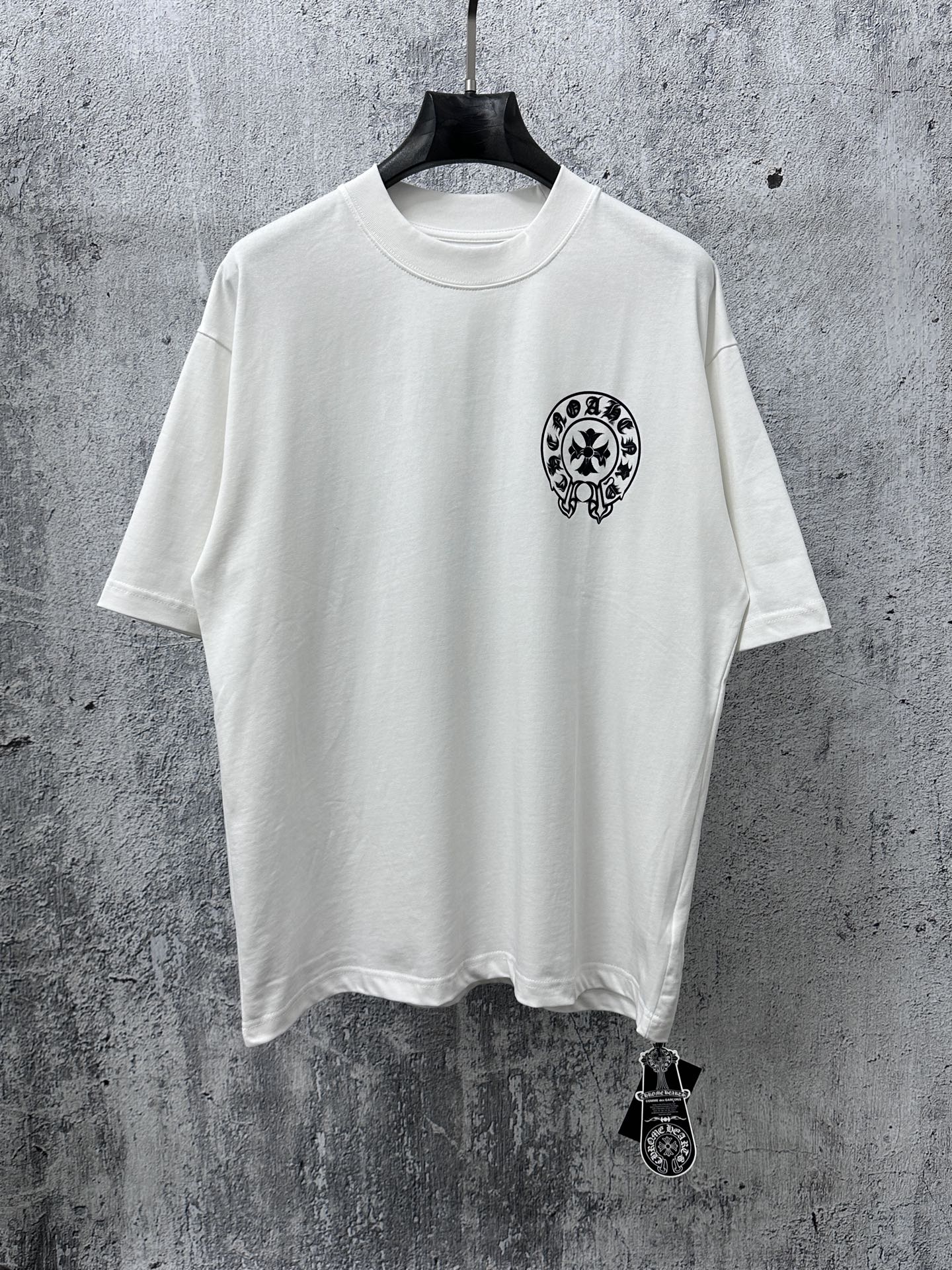White short-sleeve T-shirt with small black circular graphic on the chest