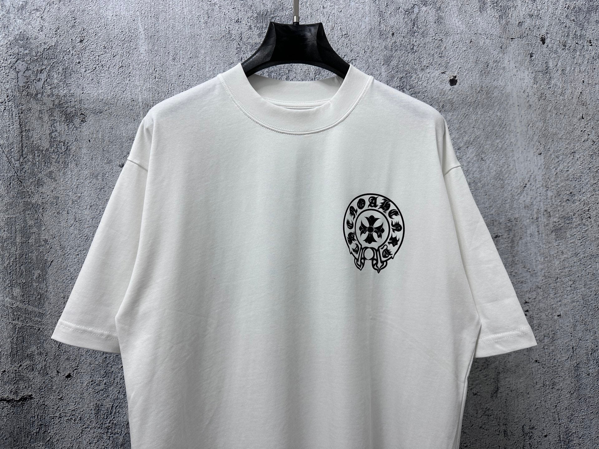 White short-sleeve T-shirt with small black circular graphic on the front