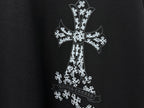Black T-shirt close-up of white cross graphic with ornate pattern