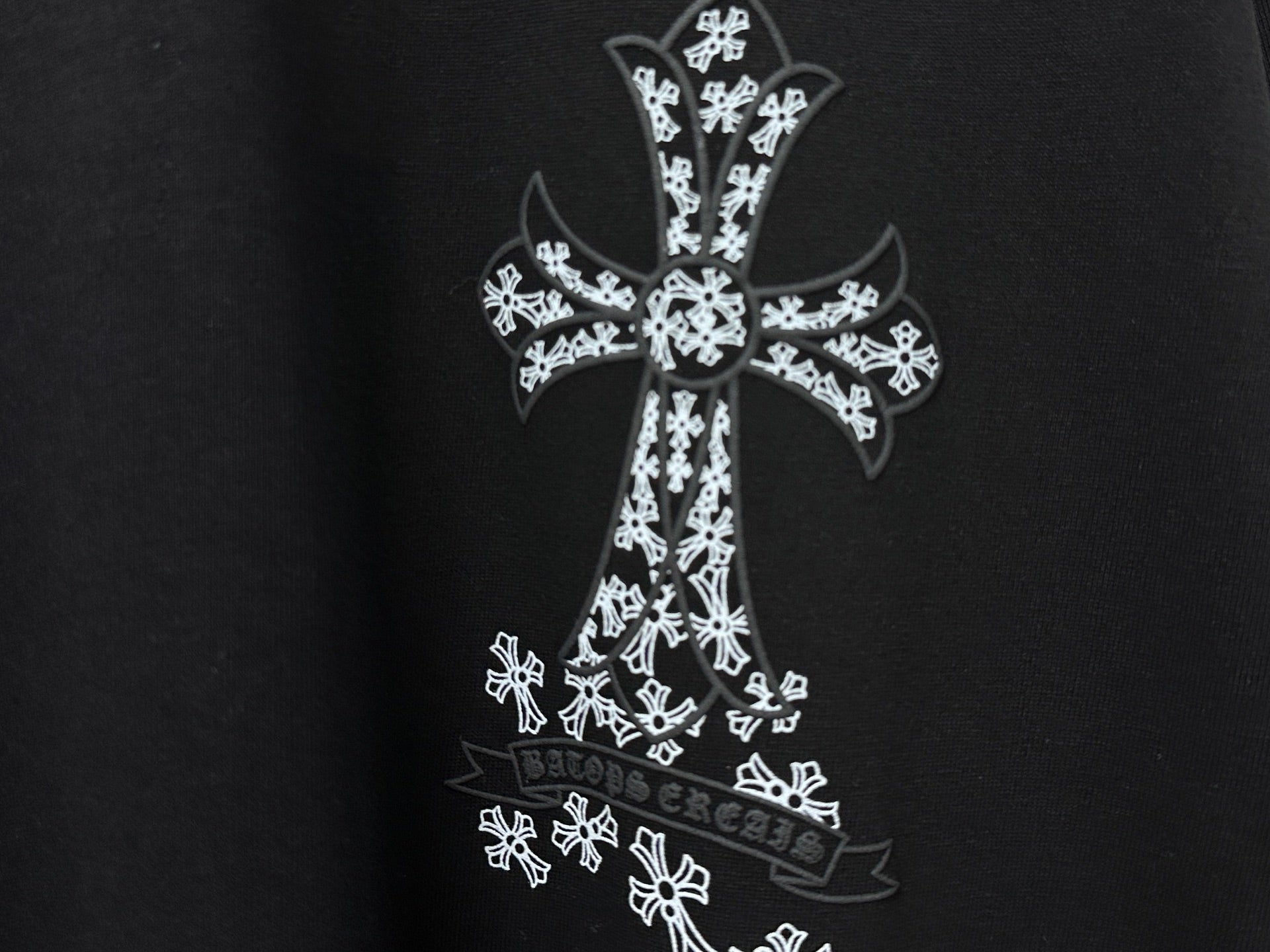 Black T-shirt close-up of white cross graphic with ornate pattern