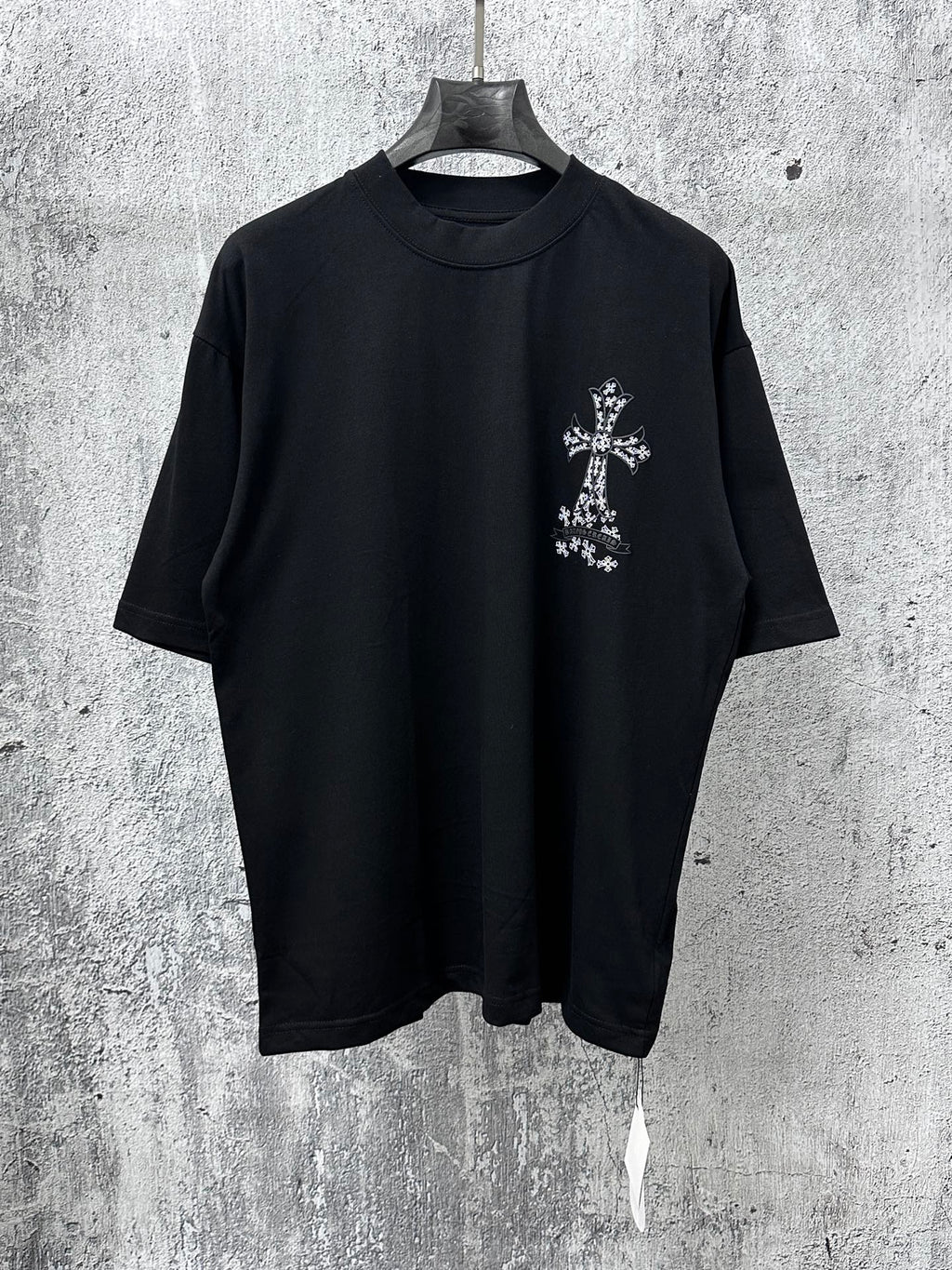 Black short-sleeve crewneck T-shirt with small white cross graphic on chest