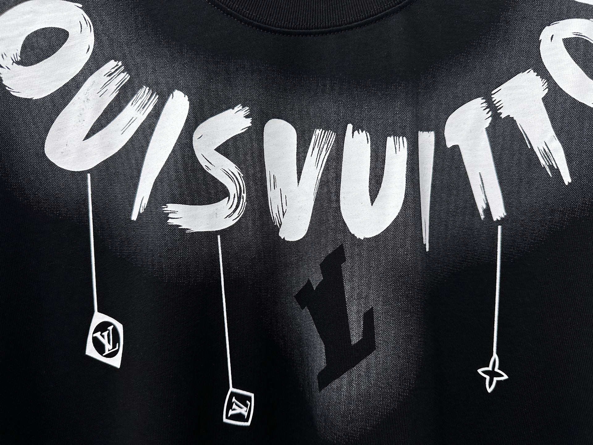 Close-up white graffiti lettering and charm graphic on black T-shirt