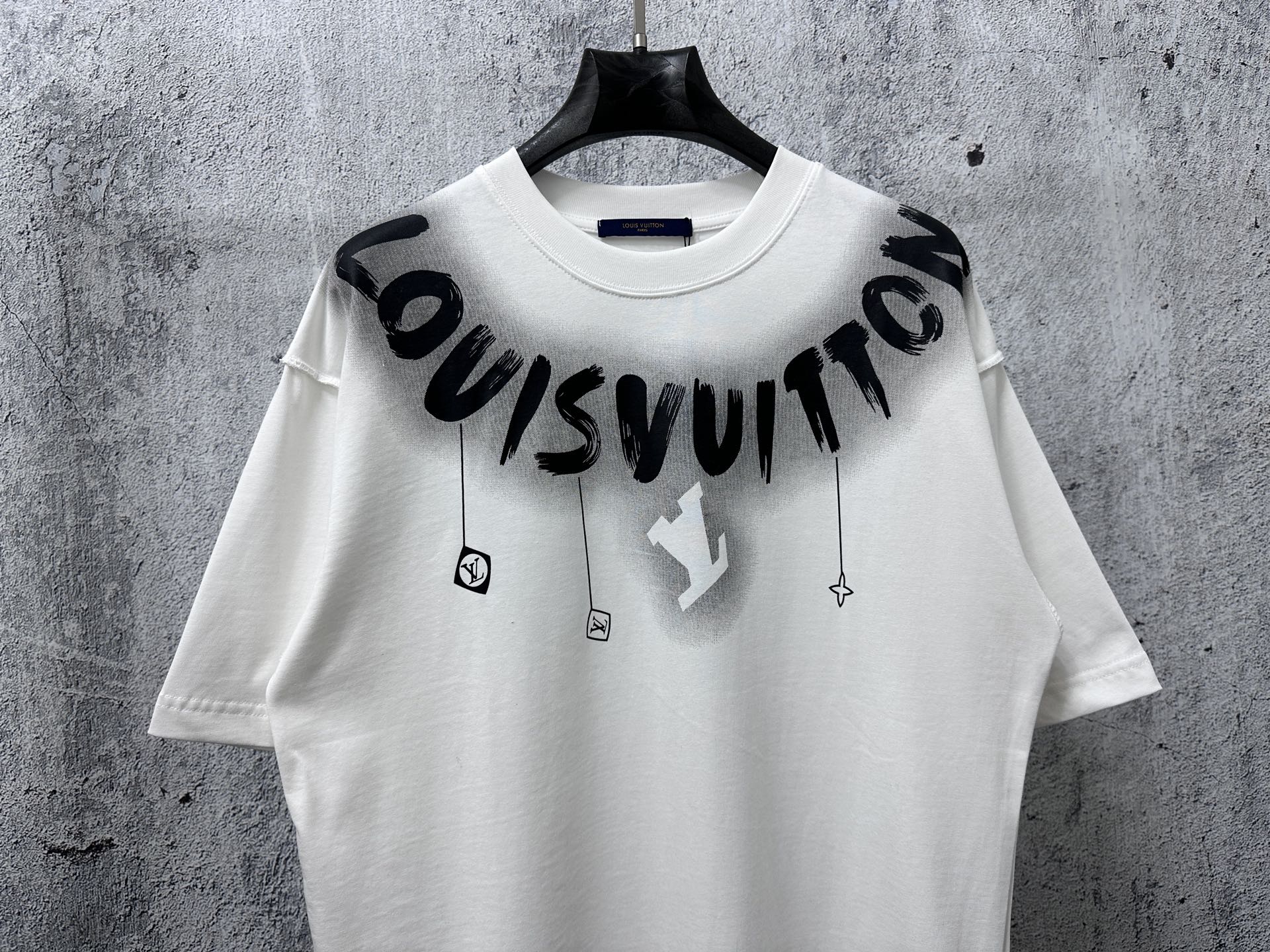 White T-shirt with black “Louisvuitton” graphic print and small hanging charm icons
