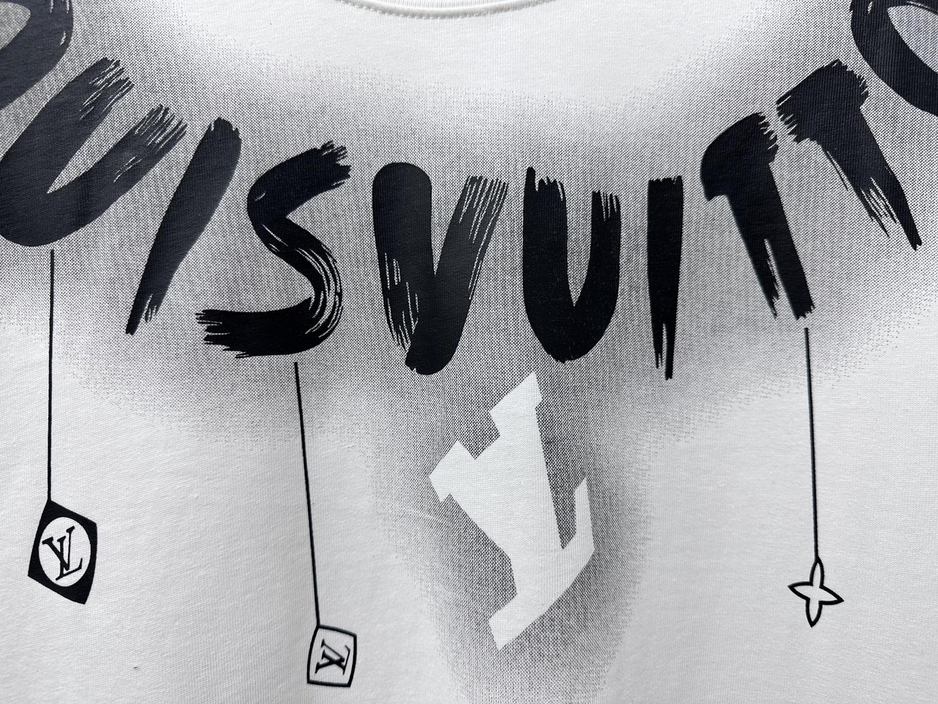 White T-shirt close-up with black “Louisvuitton” text and hanging charm icons