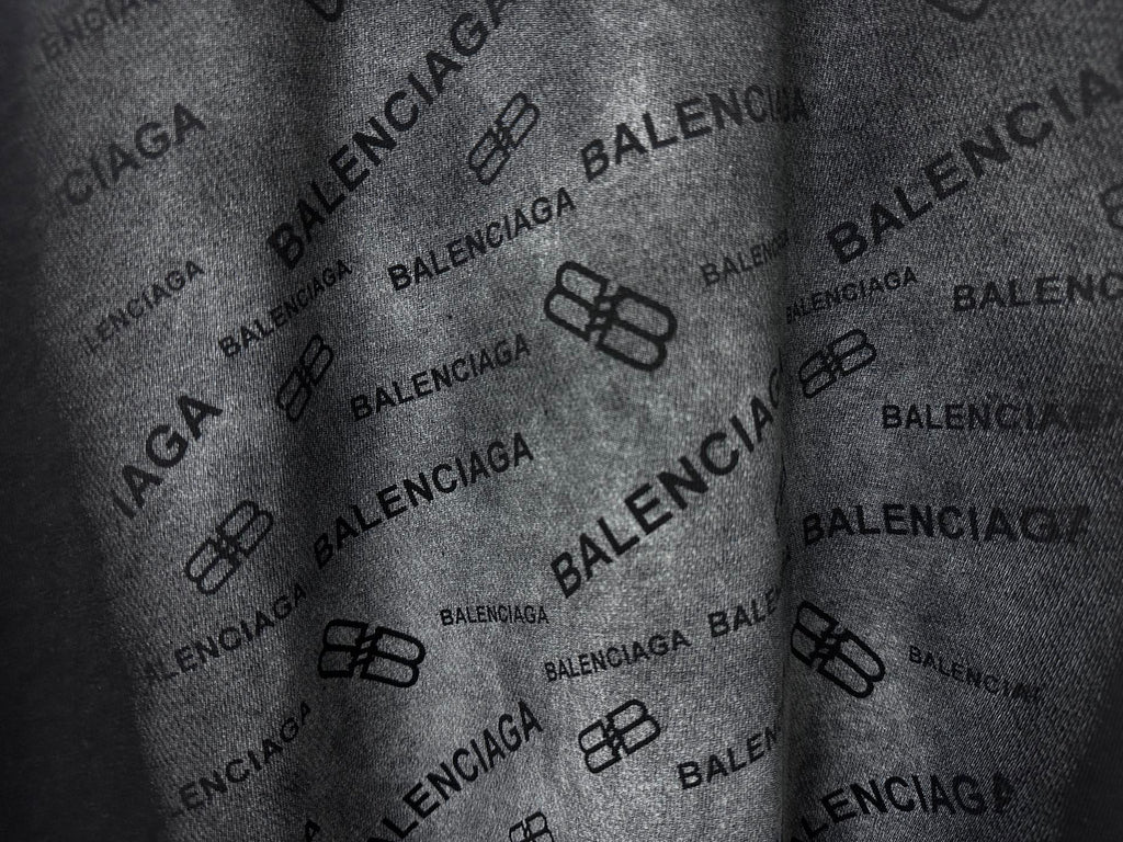 Balenciaga T-shirt fabric close-up, black with repeating Balenciaga logo pattern