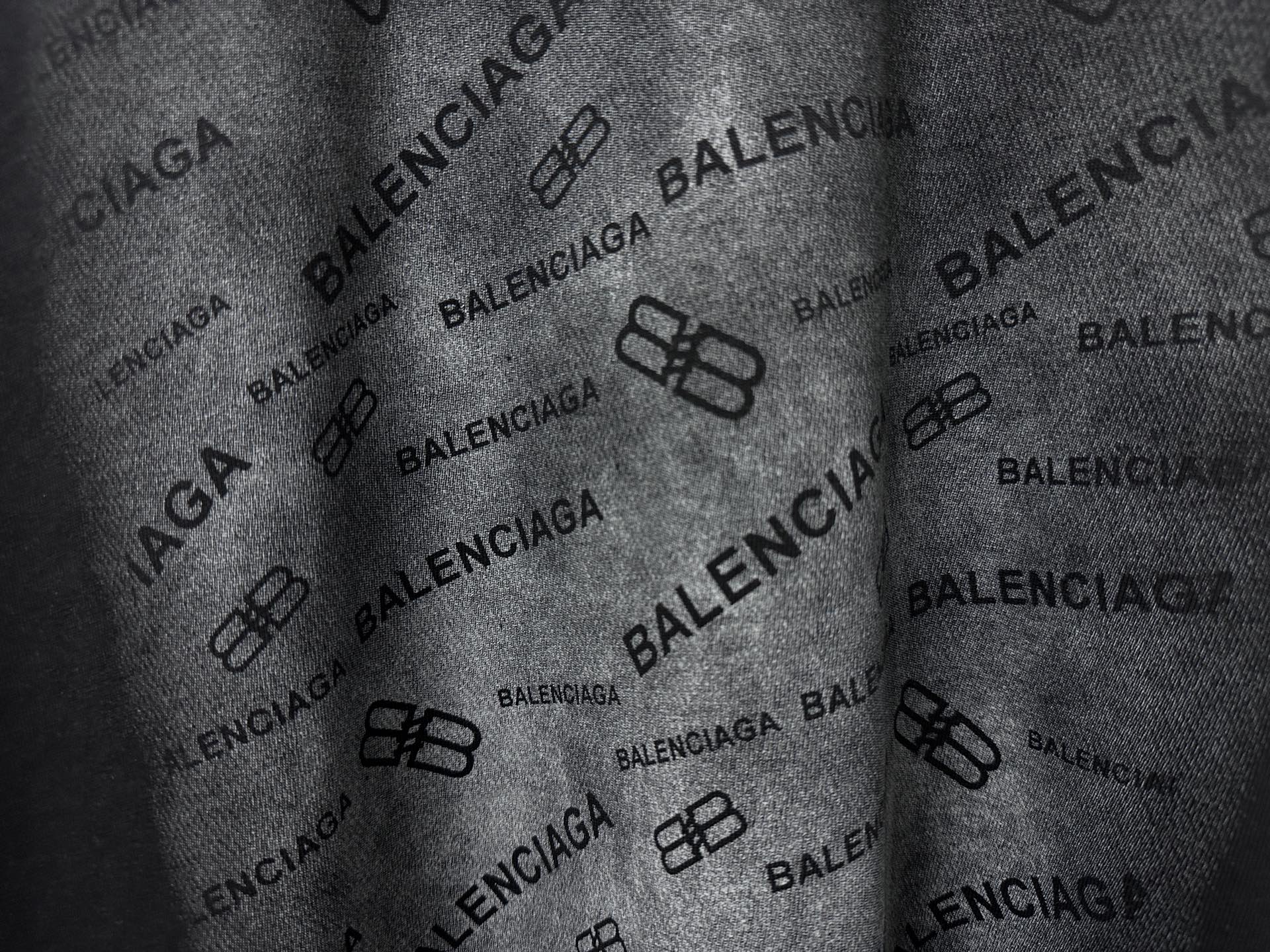 Balenciaga T-shirt fabric close-up, black with repeating Balenciaga logo pattern