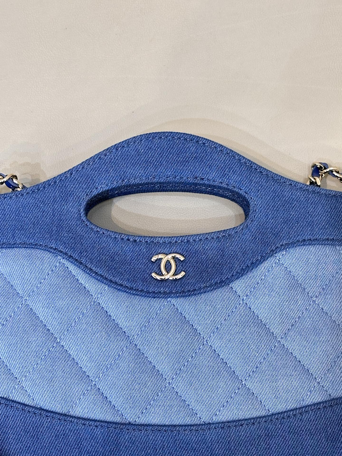 Chanel blue quilted bag close-up of oval handle cutout and stitched fabric