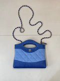 Chanel mini bag in blue with quilted pattern, top handle, and oval logo cutout