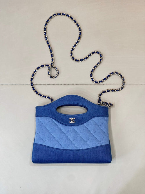 Chanel mini bag in blue with quilted pattern, top handle, and oval logo cutout