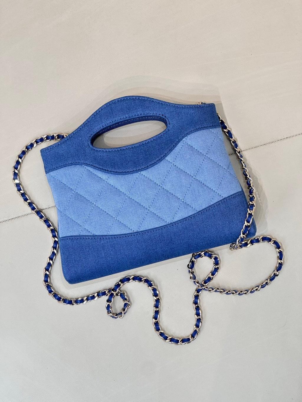 Chanel blue quilted bag angled view with oval handle cutout and chain strap