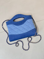 Chanel blue quilted bag angled view with oval handle cutout and chain strap