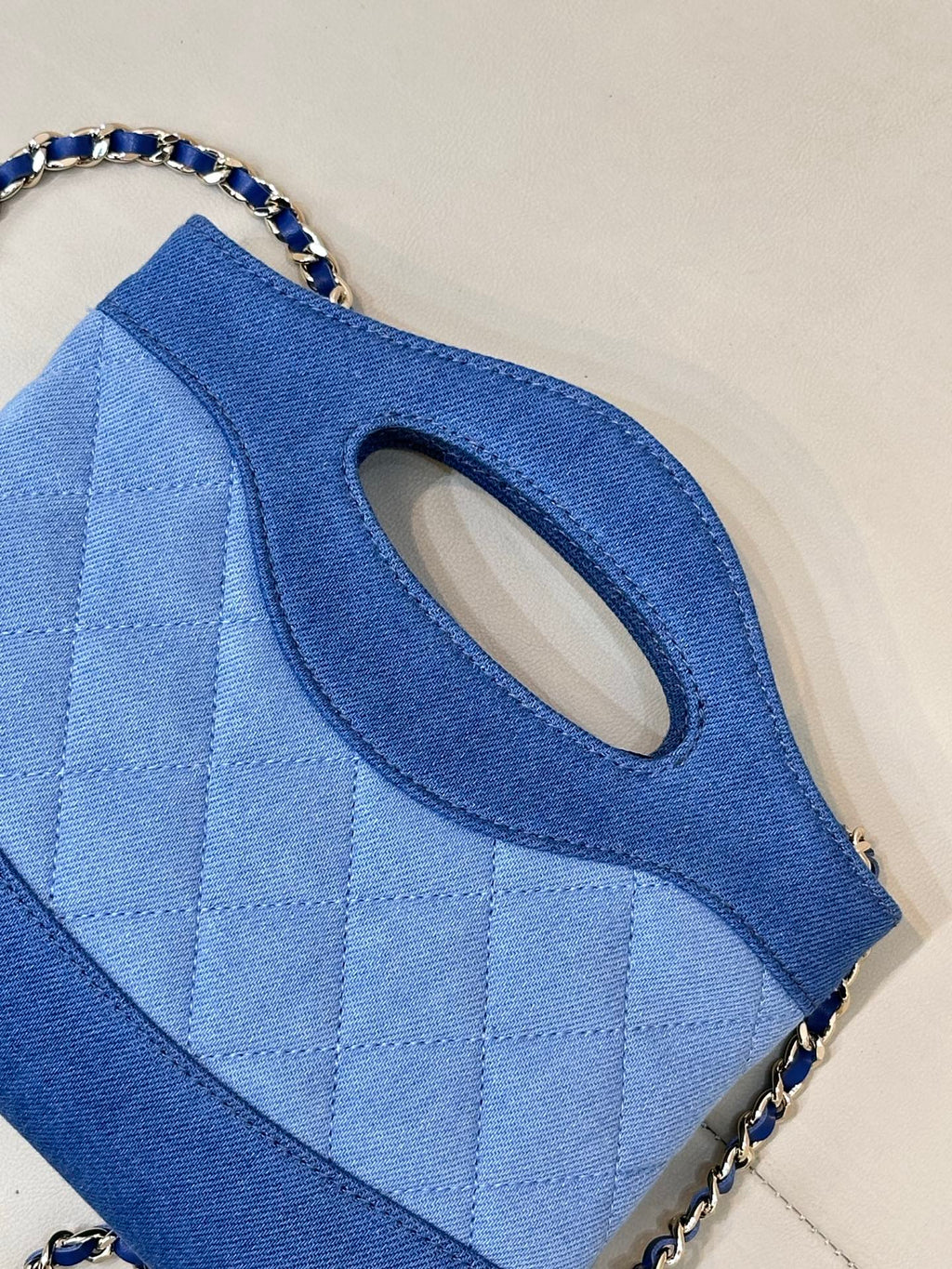 Chanel blue quilted bag close-up of oval handle cutout and chain strap