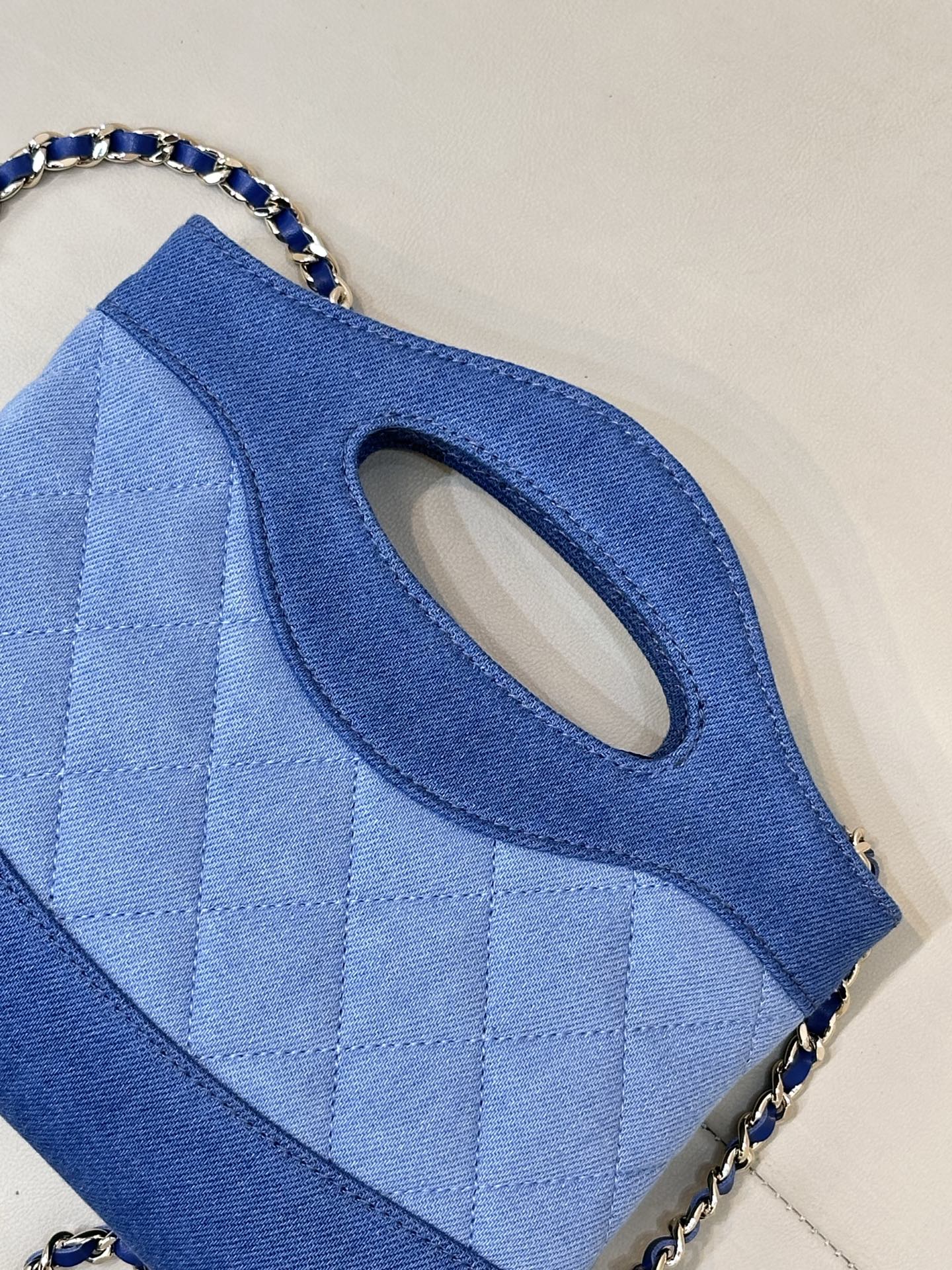 Chanel blue quilted bag close-up of oval handle cutout and chain strap