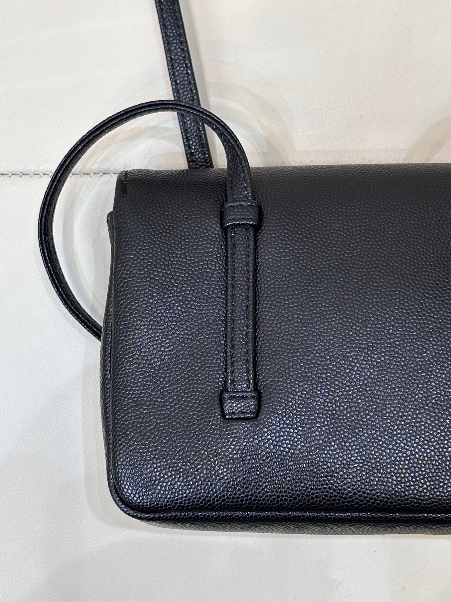 Chanel handbag close-up of side strap loop and textured dark blue leather body.