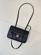 Chanel handbag with flap front and gold CC logo, shown with long shoulder strap.