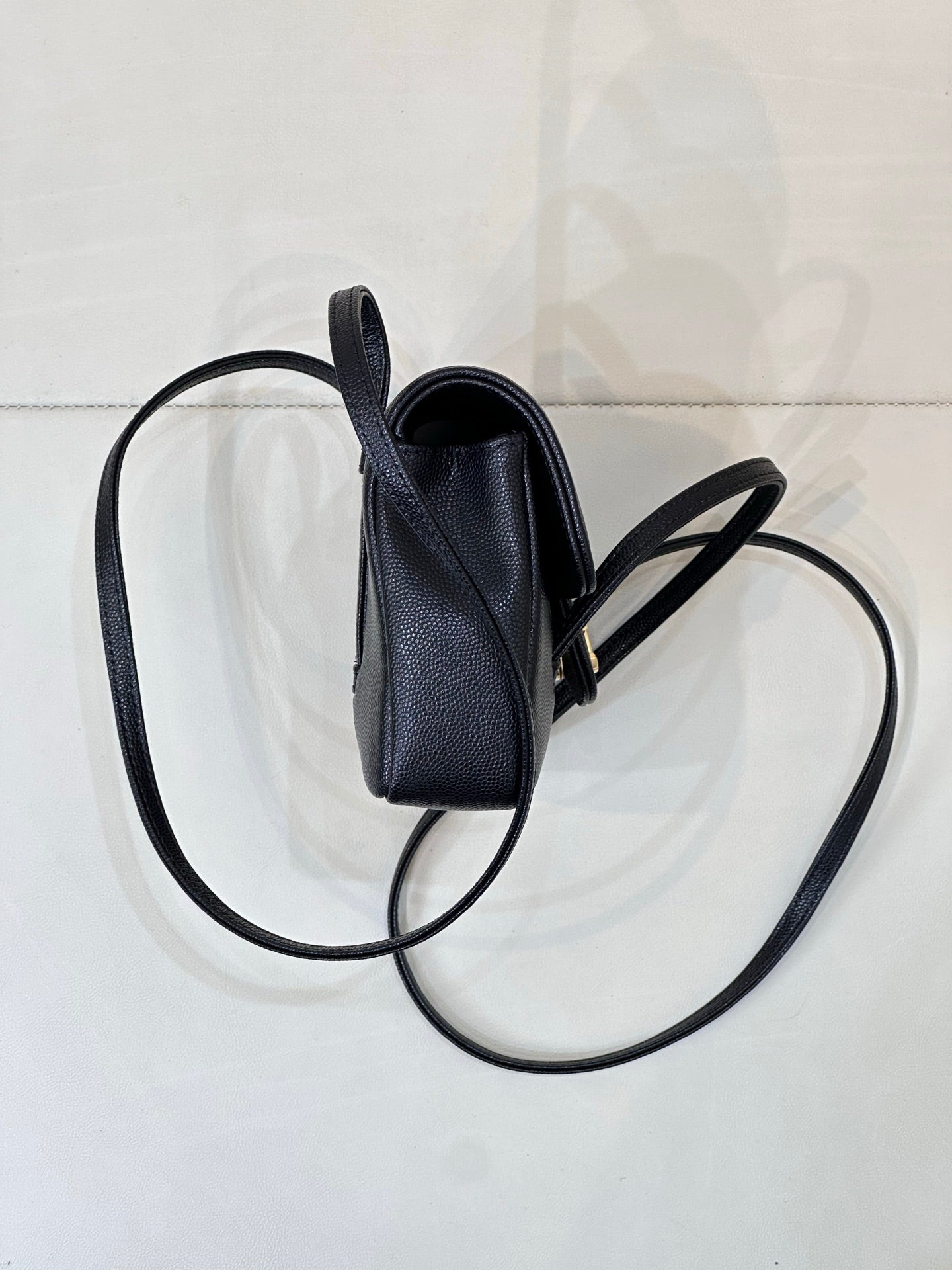 Chanel handbag side view showing top opening and crossbody strap.