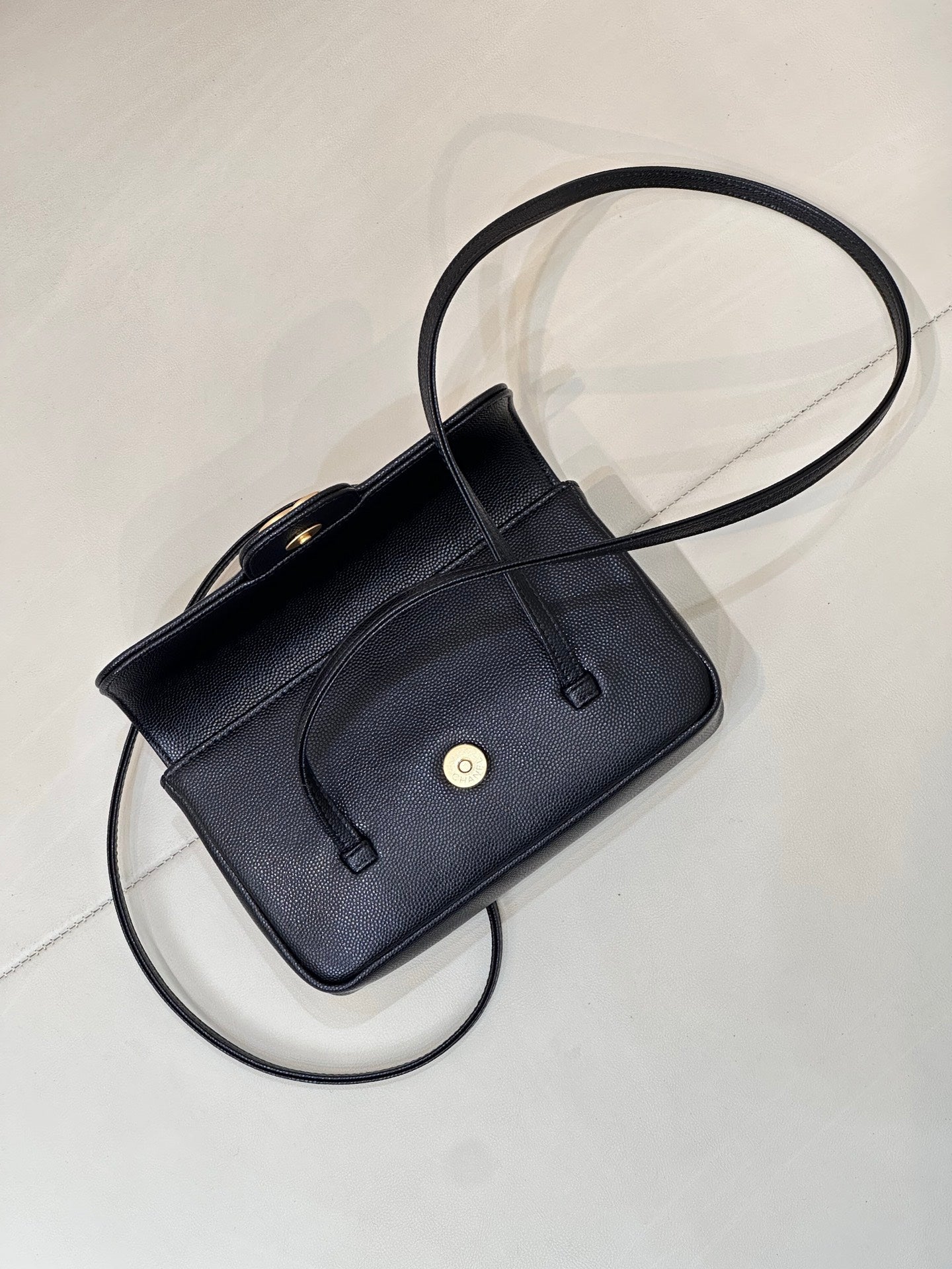 Chanel handbag with flap front, gold-tone button hardware, and shoulder strap.