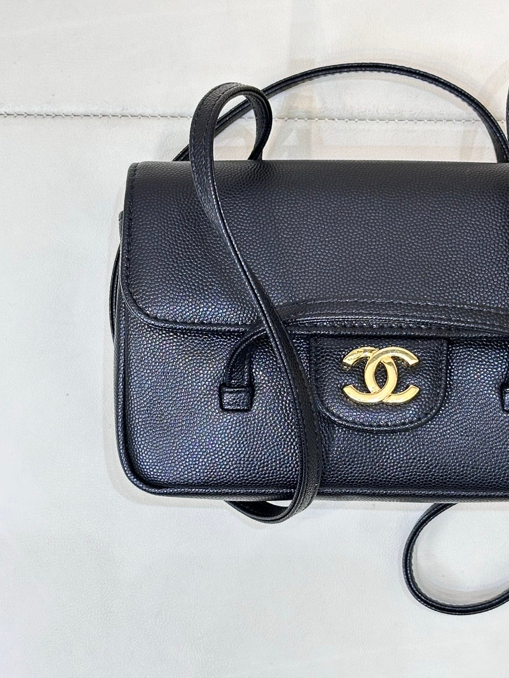 Chanel handbag close-up with flap and gold CC logo detail, dark blue leather texture.