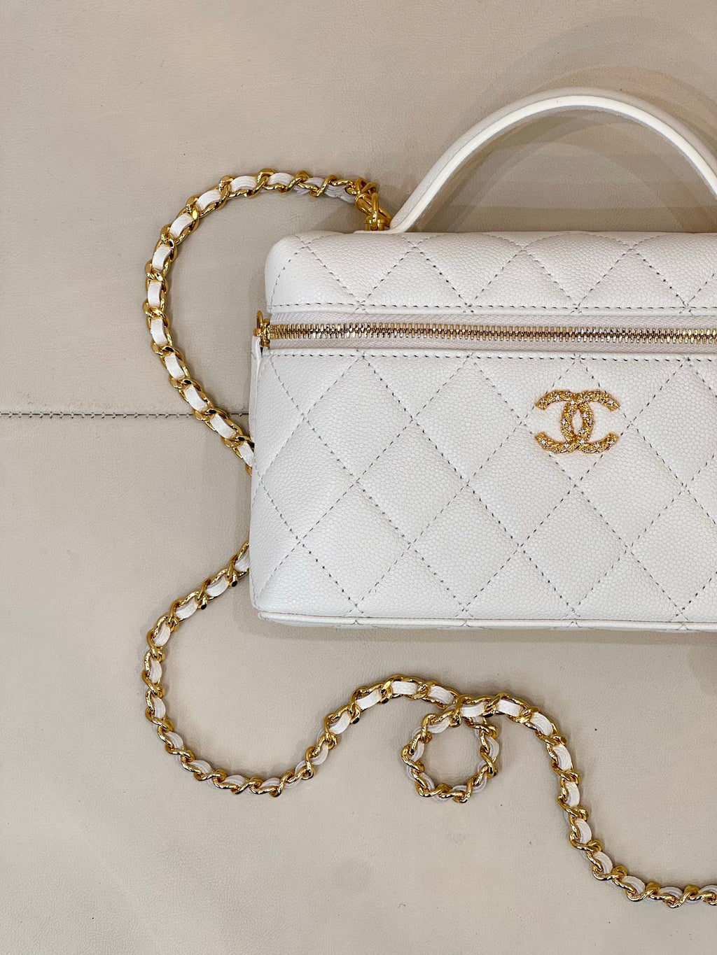 White quilted leather bag close-up with gold zipper and gold chain strap.