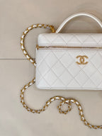 White quilted leather bag close-up with gold zipper and gold chain strap.