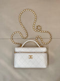 White quilted leather bag with top handle, zip closure, and gold chain strap.
