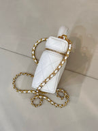 White quilted leather bag side view with gold chain strap and top handle.