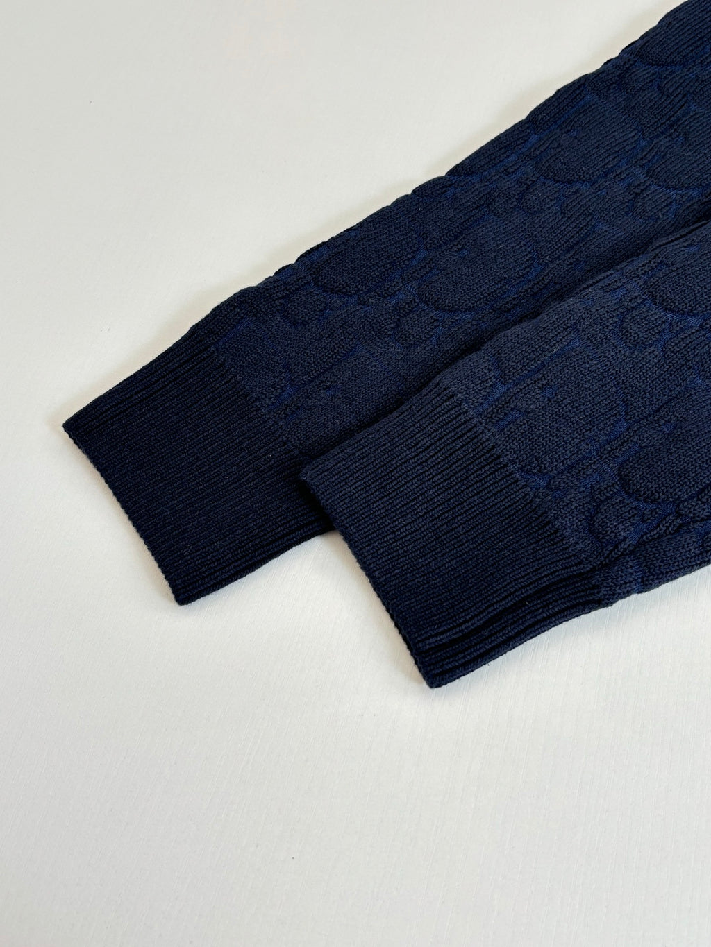 Dark navy cable-knit sweater fabric and sleeve edge detail.