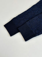 Dark navy cable-knit sweater fabric and sleeve edge detail.