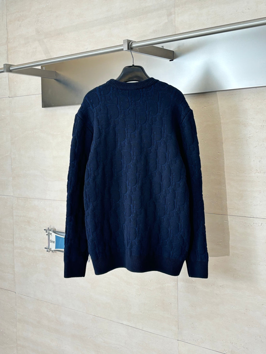 Dark navy cable-knit long-sleeve sweater back view on hanger.
