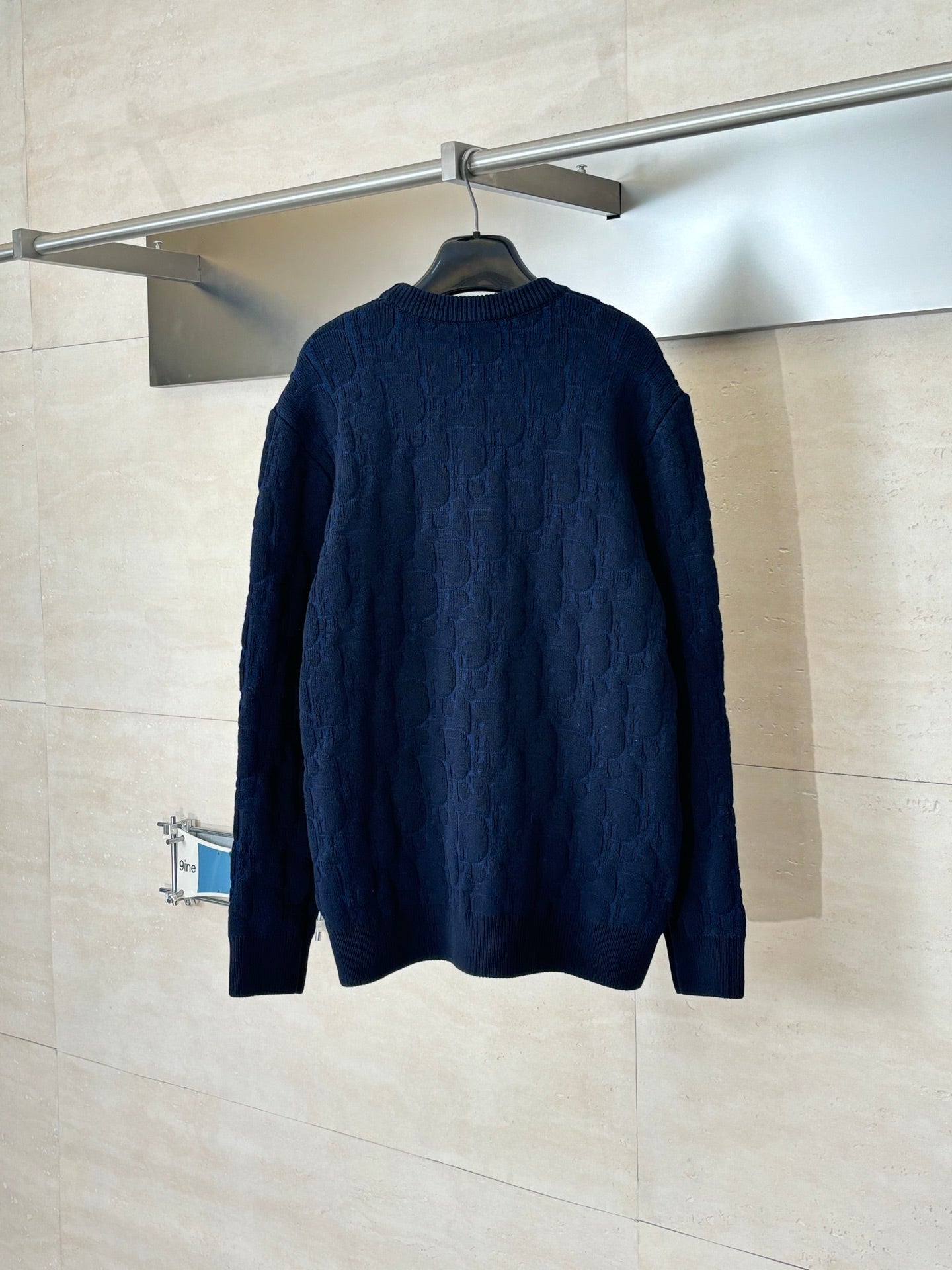 Dark navy cable-knit long-sleeve sweater back view on hanger.