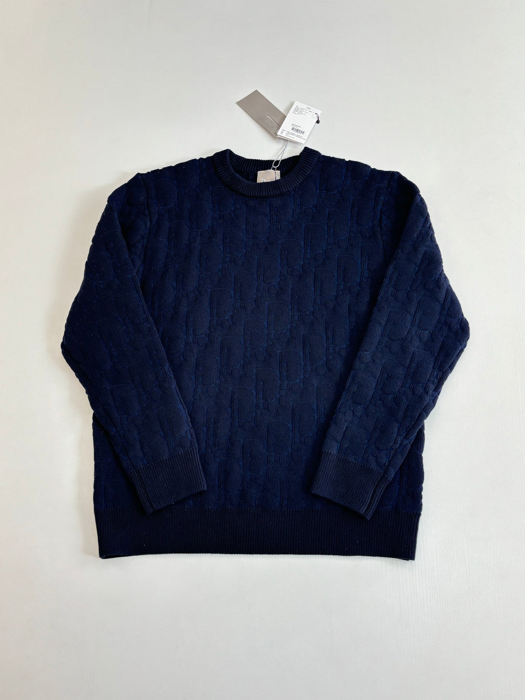 Dark navy cable-knit crewneck sweater with long sleeves, laid flat.