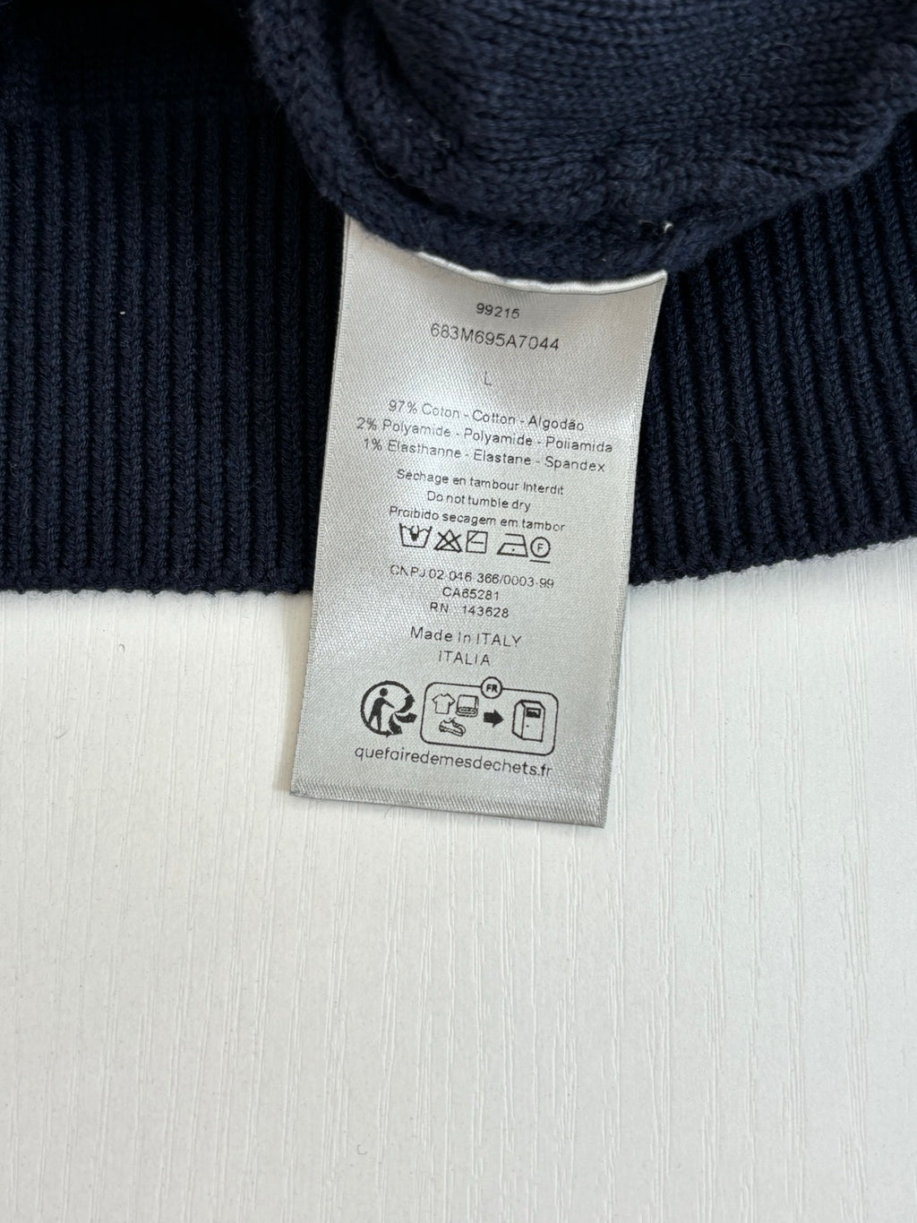 Dark navy sweater care label on ribbed knit collar, tag attached.