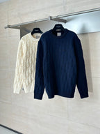 Dark navy cable-knit sweater on hanger next to cream sweater.