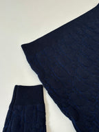 Dark navy cable-knit sweater sleeve with ribbed hem detail.
