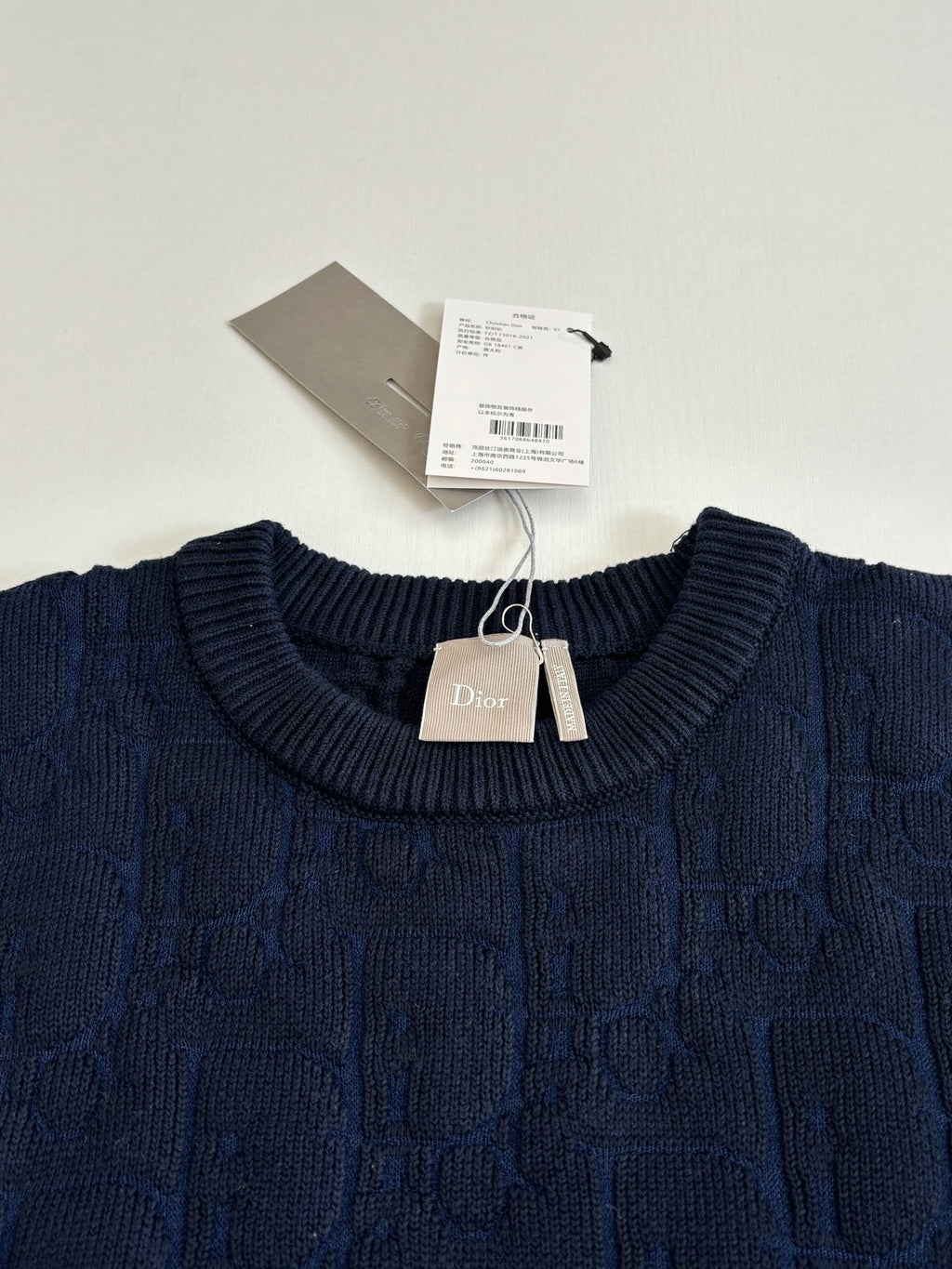 Dark navy cable-knit crewneck sweater with Dior tag at collar.