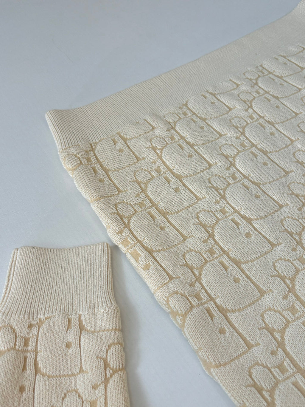 Cream knit legwarmers with allover Dior-style logo pattern and ribbed cuffs